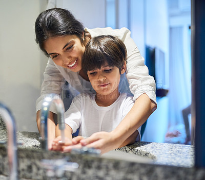 Buy stock photo Shot of a mother helping her little son wash his hands in the bathroom