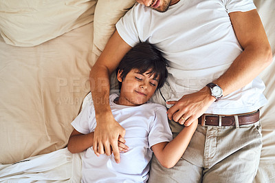 Buy stock photo High angle shot of a little boy sleeping alongside his father in bed at home