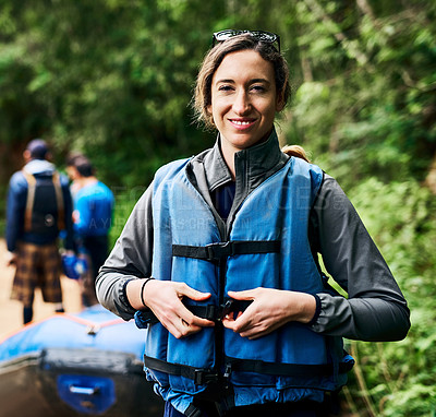 Buy stock photo Portrait of a cheerful young woman putting on a life jacket to go river rafting outside during the day