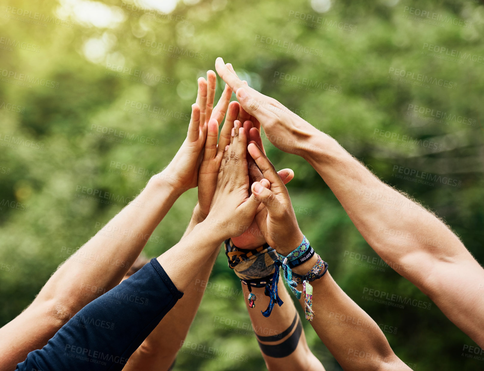 Buy stock photo Shot of a group of unrecognizable people's hands raised in the air to form a huddle together outside during the day