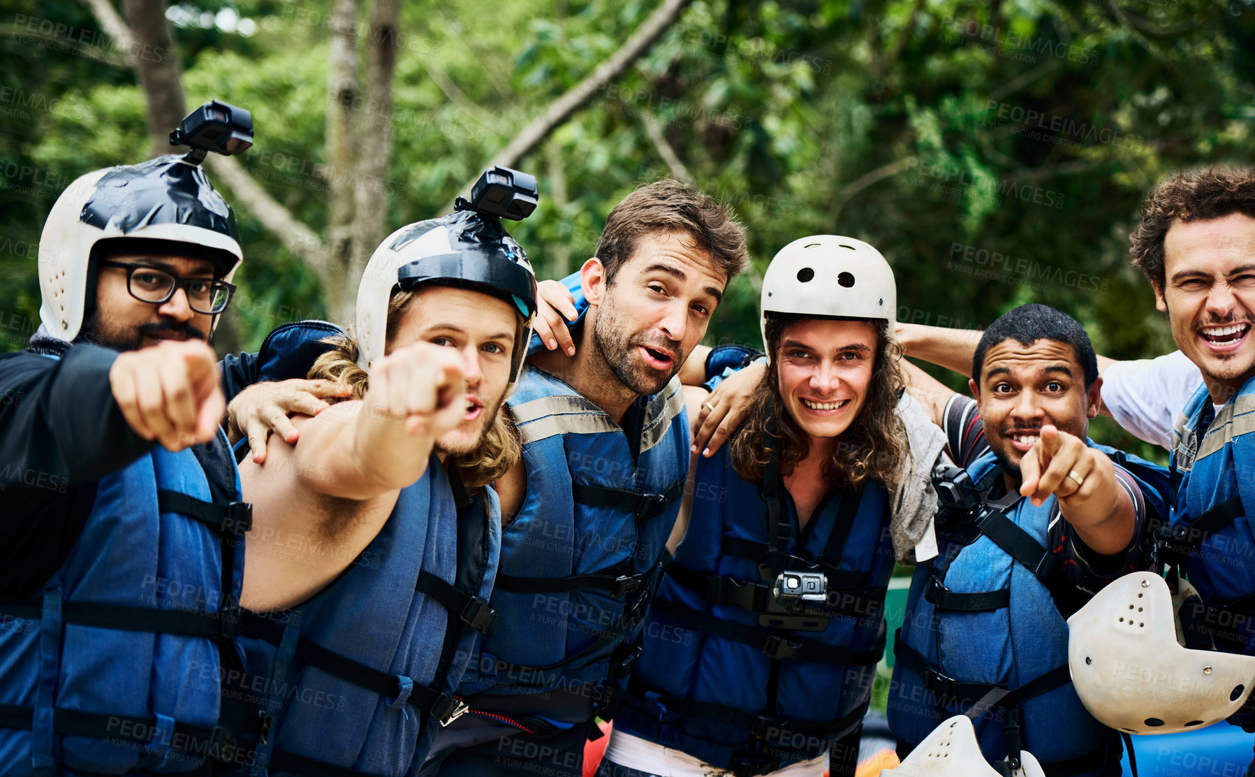 Buy stock photo Portrait of a group of cheerful young men wearing protective gear and standing arm in arm ready to go river rafting outside during the day
