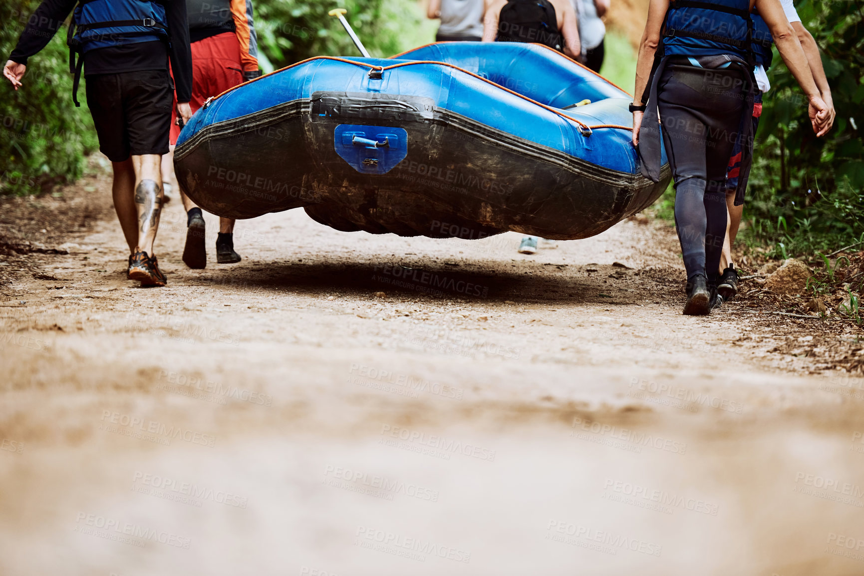 Buy stock photo Low angle shot of a group of unrecognizable people carrying a rubber boat together to go river rafting outside during the day