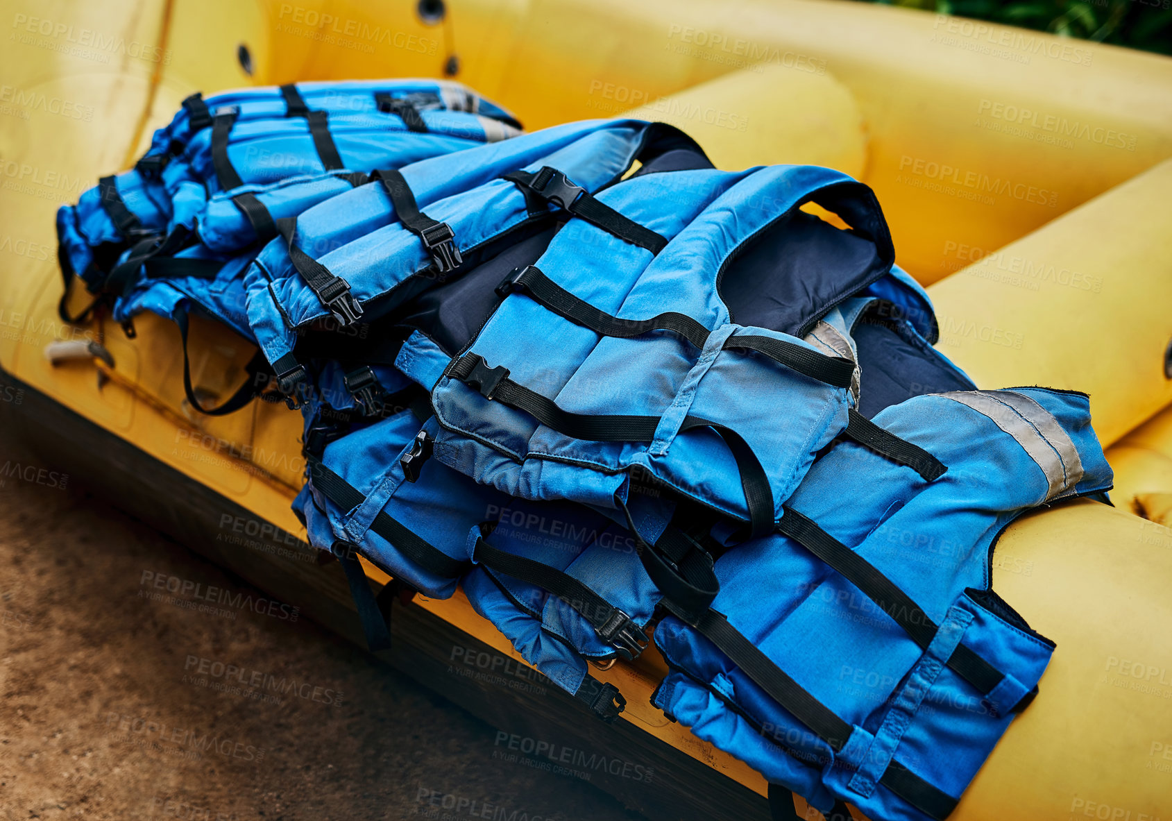 Buy stock photo Shot of a pile of river rafting life jackets lying on top of a rubber river rafting boat outside during the day