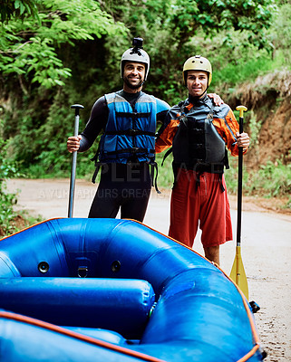 Buy stock photo Portrait of two cheerful young men wearing protective gear while each holding a paddle to go river rafting