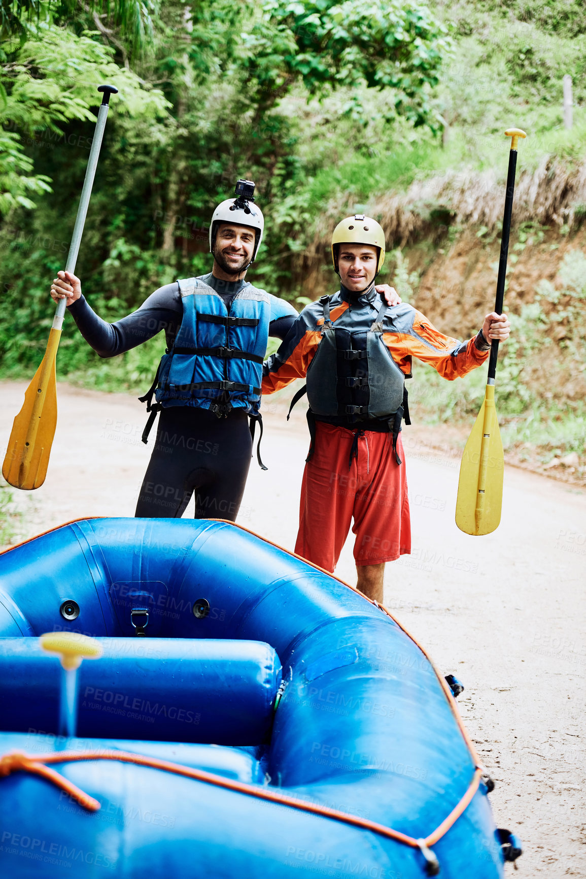 Buy stock photo Portrait of two cheerful young men wearing protective gear while each holding a paddle to go river rafting