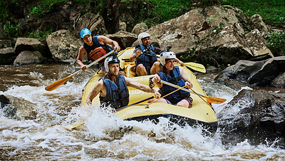 Buy stock photo Shot of a group of determined young men on a rubber boat busy paddling on strong river rapids outside during the day