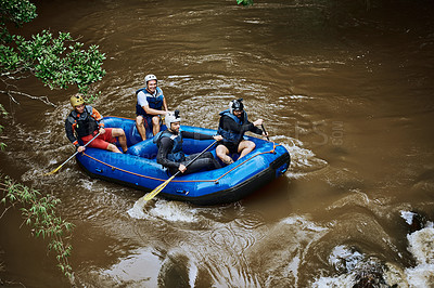 Buy stock photo High angle shot of a group of cheerful young people in a rubber boat paddling on a river outside during the day