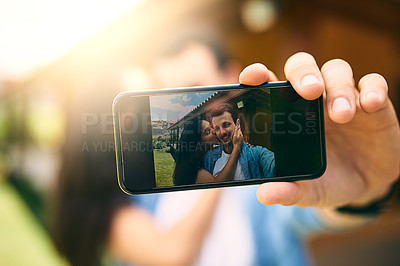 Buy stock photo Happy couple, kiss and phone camera for selfie, photo or profile picture together in relationship outdoors. Hand of man holding smartphone with woman kissing cheek for love, memory or capture outside