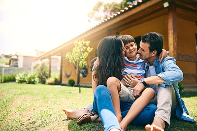 Buy stock photo Cropped shot of a happy young family of three sitting on their lawn in the backyard