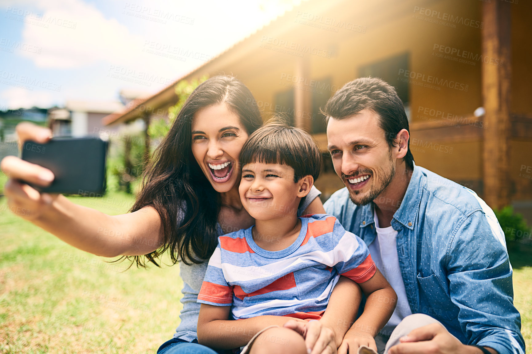 Buy stock photo Cropped shot of a happy young family of three taking selfies white sitting in the backyard