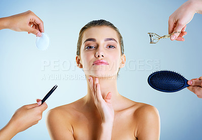 Buy stock photo Studio portrait of a beautiful young woman with an assortment of beauty tools around her against a blue background