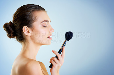 Buy stock photo Studio shot of a beautiful young woman holding a makeup brush against a blue background