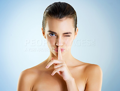Buy stock photo Studio portrait of a beautiful young woman with her finger to her lips against a blue background
