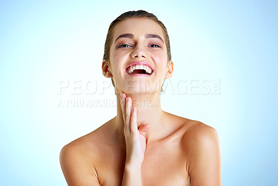 Buy stock photo Studio portrait of a beautiful young woman feeling her skin against a blue background