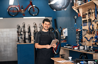 Buy stock photo Shot of a man using a digital tablet in a bicycle repair shop