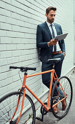 Buy stock photo Man, tablet and bicycle by wall with suit in city, commute or sustainable travel in metro. Business person, bike and digital touchscreen for eco friendly transport, app and check schedule in Madrid