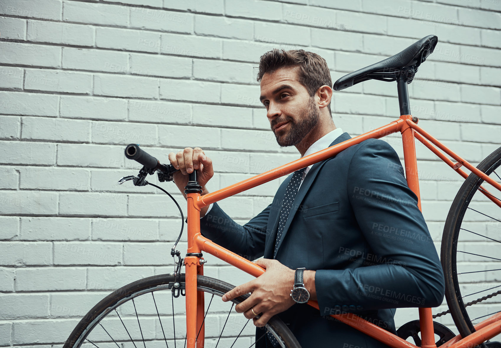 Buy stock photo Shot of a handsome young businessman carrying his bike on his shoulder outdoors