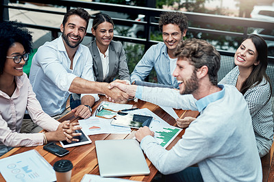 Buy stock photo Shot of businesspeople shaking hands during a meeting at a cafe