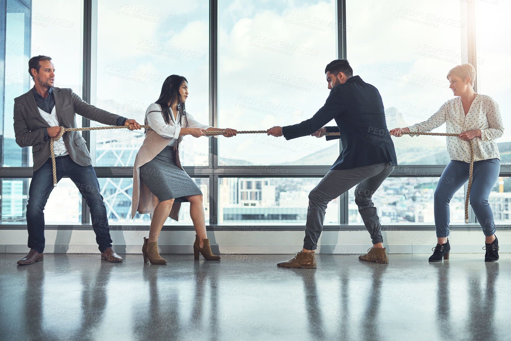 Buy stock photo Shot of a group of businesspeople pulling on a rope during tug of war in an office