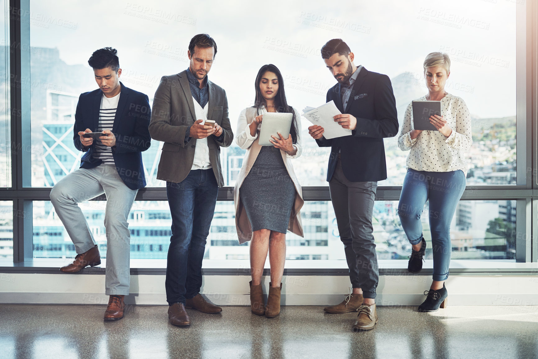 Buy stock photo Shot of a diverse group of businesspeople using wireless technology in an office