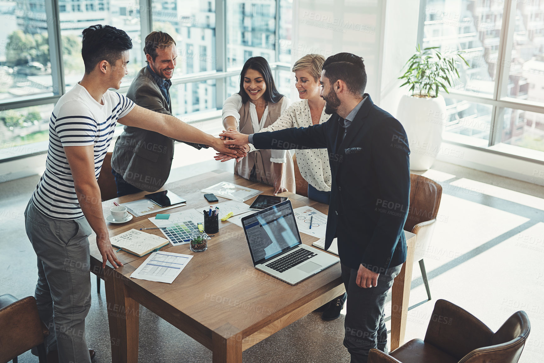 Buy stock photo Shot of a diverse group of businesspeople joining their hands in a huddle in an office