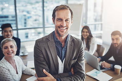 Buy stock photo Portrait of a mature businessman standing in an office with his colleagues in the background
