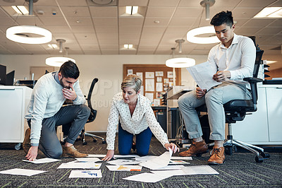 Buy stock photo Shot of businesspeople working on paperwork together on the floor in the office