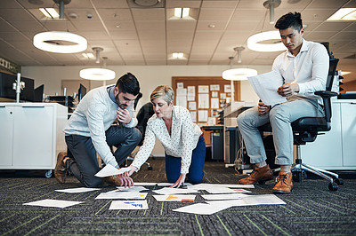 Buy stock photo Shot of businesspeople working on paperwork together on the floor in the office