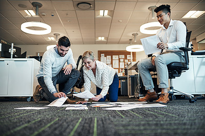 Buy stock photo Shot of businesspeople working with paperwork together on the floor in the office