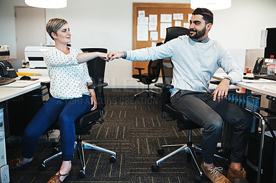 Buy stock photo Shot of creative colleagues giving each other a fist pound in the office