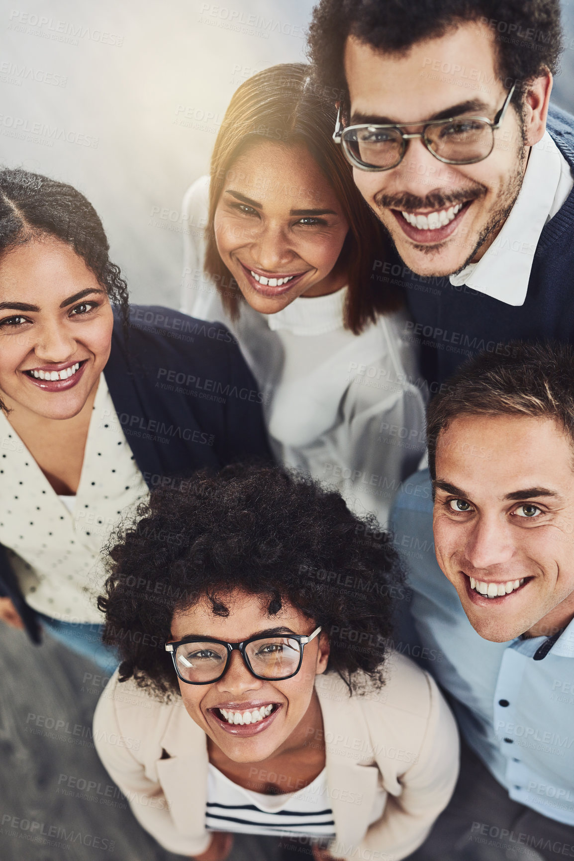 Buy stock photo Diverse group of creative colleagues from above looking excited, happy or motivated and ready to take startup business to the top. Portrait of smiling, happy and cheerful office team standing united
