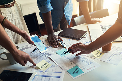 Buy stock photo High angle shot of a group of unrecognizable businesspeople looking over some paperwork in the boardroom