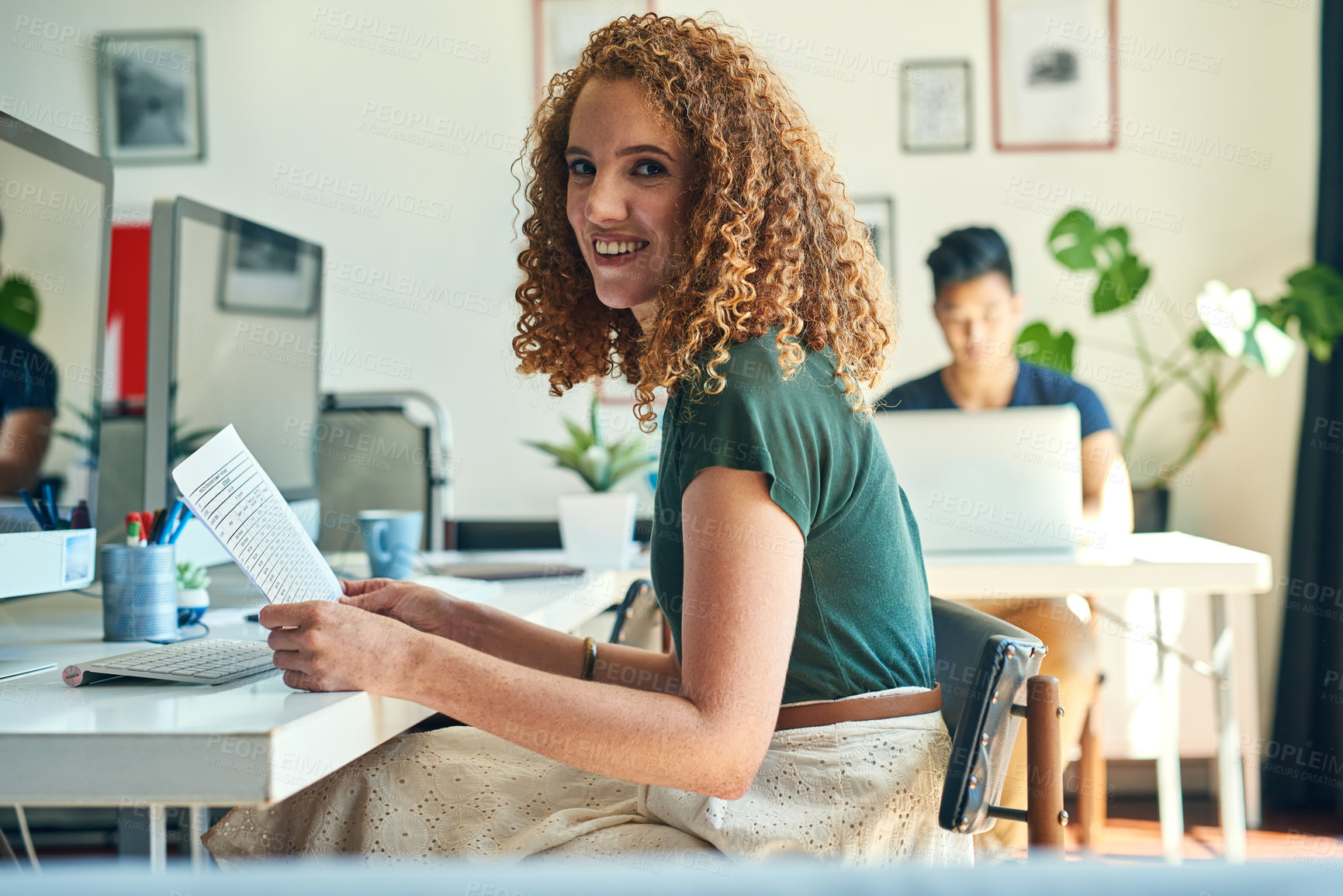 Buy stock photo Cropped portrait of an attractive young female designer reading over some paperwork in the office
