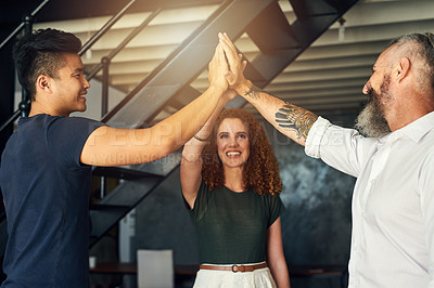 Buy stock photo Cropped shot of three creative businesspeople high fiving in their office