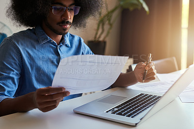 Buy stock photo Cropped shot of a handsome male designer looking at some paperwork while working in his office