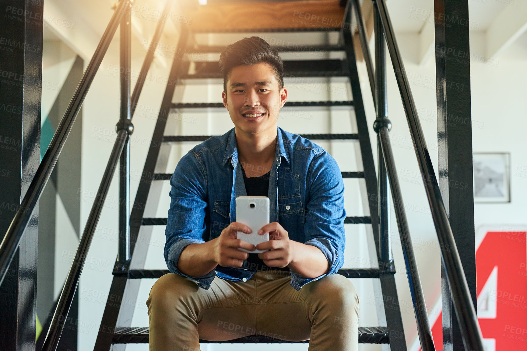 Buy stock photo Cropped portrait of a handsome young male designer sending a text message in the office