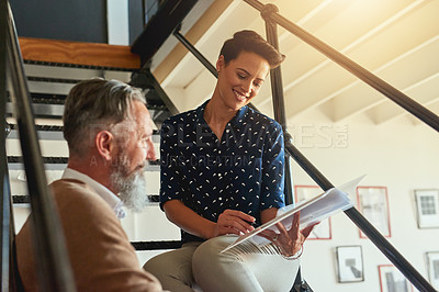 Buy stock photo Shot of creative colleagues discussing a document on steps in a modern office