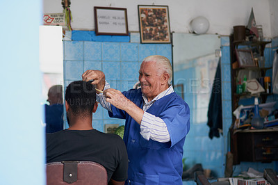 Buy stock photo Shot of a senior man trimming a client's hair in his barber shop