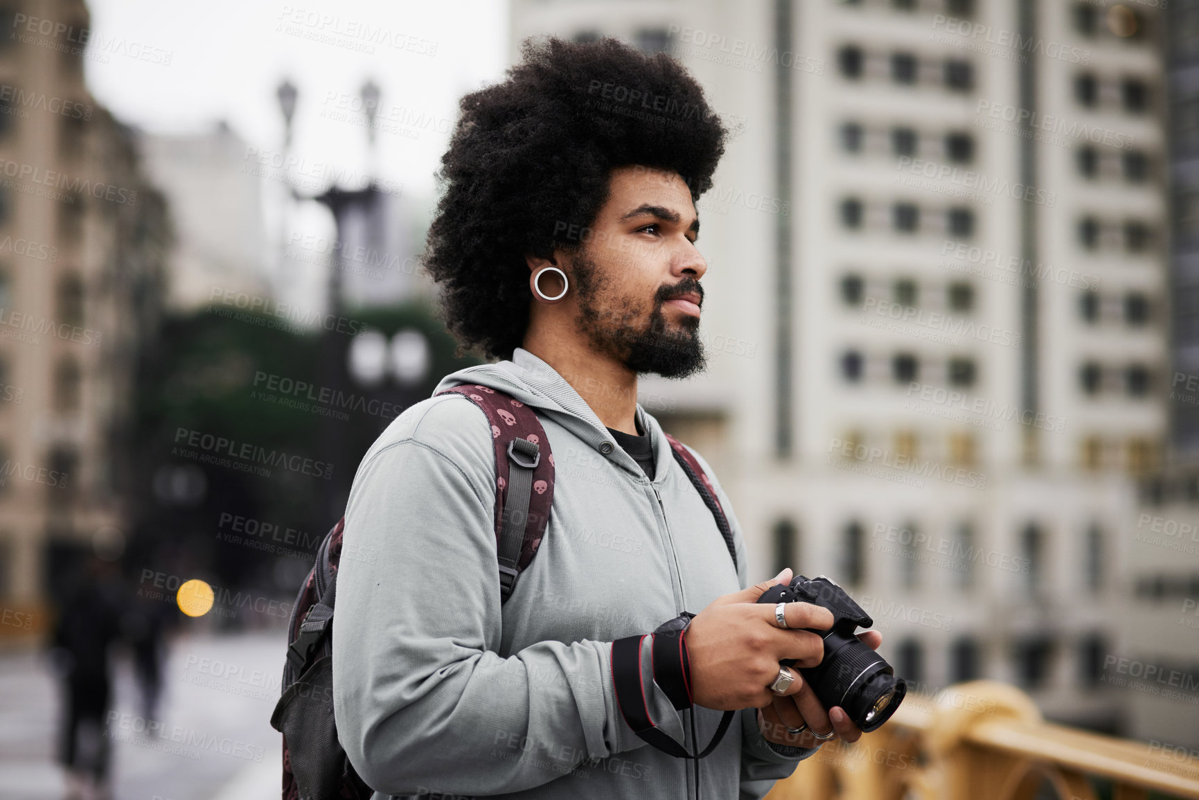 Buy stock photo Shot of a young man taking pictures with a camera in the city