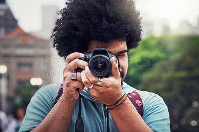 Buy stock photo Shot of a young man taking pictures with a camera in the city