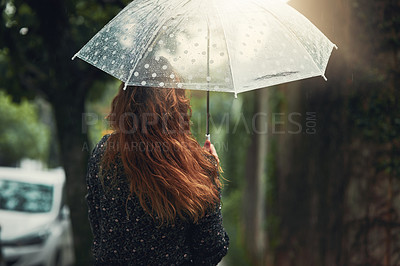 Buy stock photo Rearview shot of an unrecognizable woman walking in the rain outside