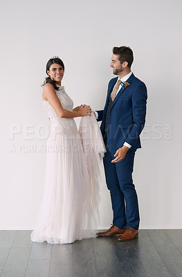 Buy stock photo Studio portrait of a newly married young couple standing against a gray background
