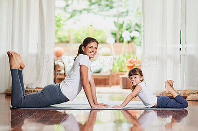 Buy stock photo Portrait of a cheerful young mother and daughter doing a yoga pose together while lying down on the ground