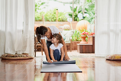 Buy stock photo Shot of a cheerful young mother and daughter doing a yoga pose together while being seated on the ground