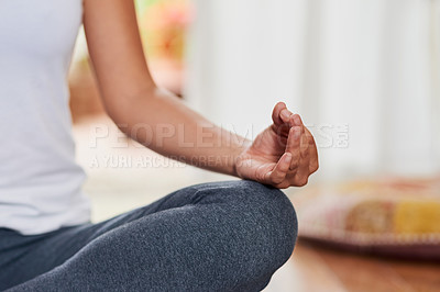 Buy stock photo Shot of an unrecognizable woman doing a yoga pose with her legs grossed and seated on the ground at home