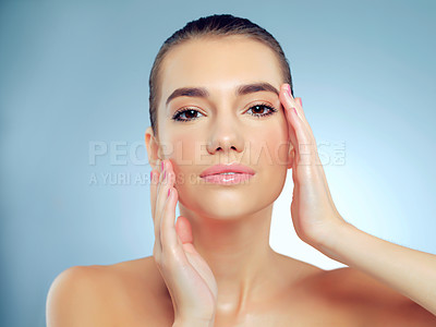 Buy stock photo Studio portrait of a beautiful young woman feeling her skin against a blue background