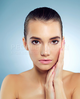 Buy stock photo Studio portrait of a beautiful young woman feeling her skin against a blue background