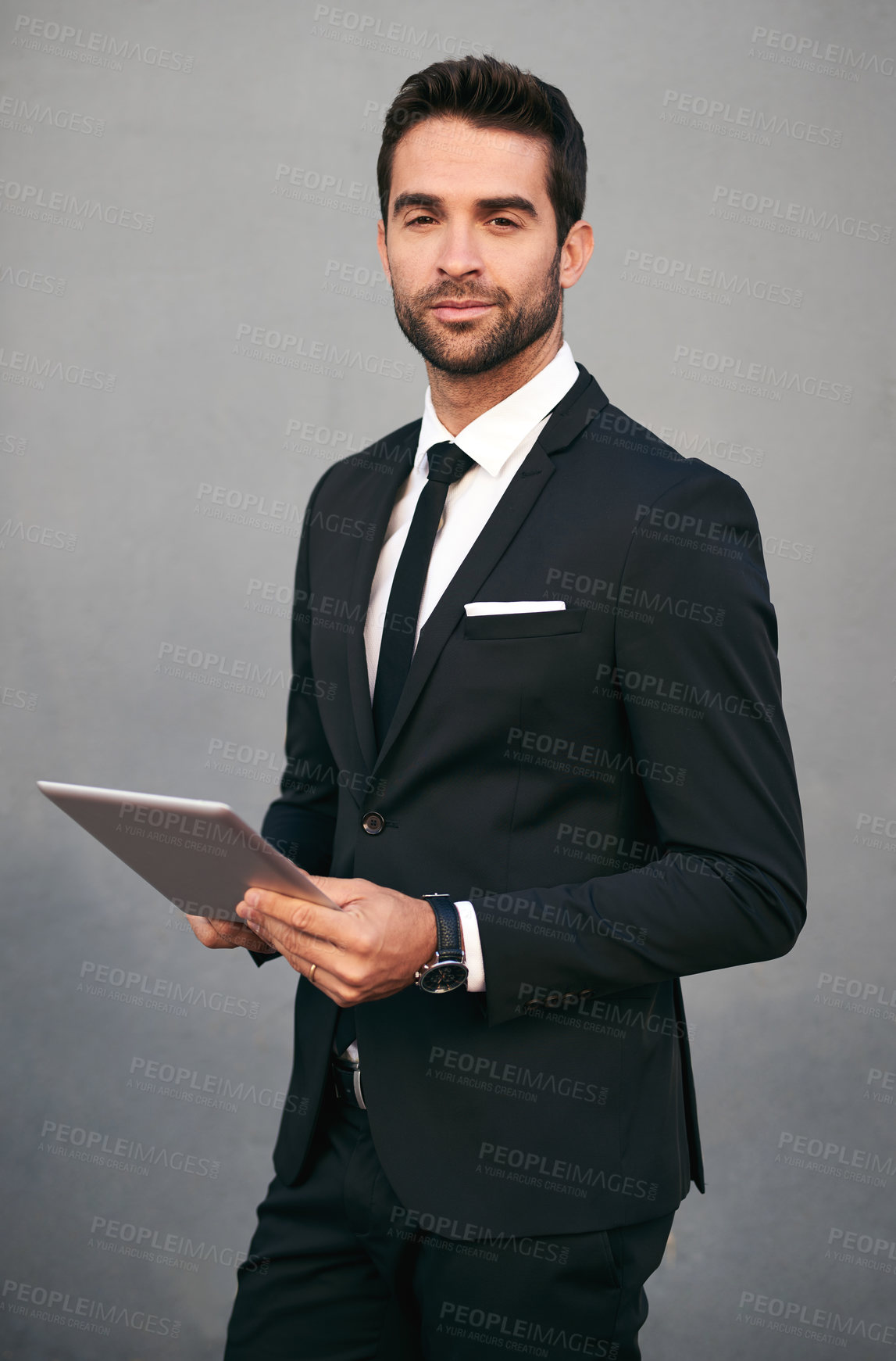 Buy stock photo Studio portrait of a handsome young businessman using a tablet against a grey background