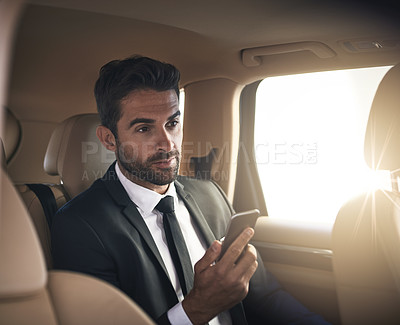Buy stock photo Cropped shot of a handsome young businessman sending a text message while on his morning commute to work
