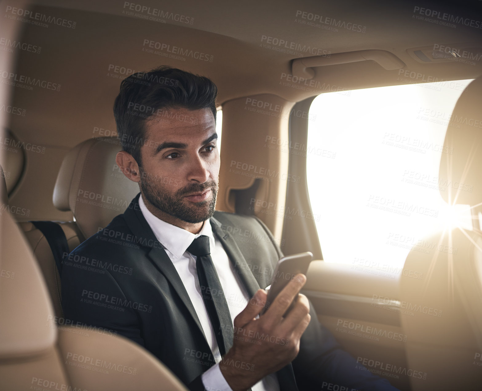 Buy stock photo Cropped shot of a handsome young businessman sending a text message while on his morning commute to work